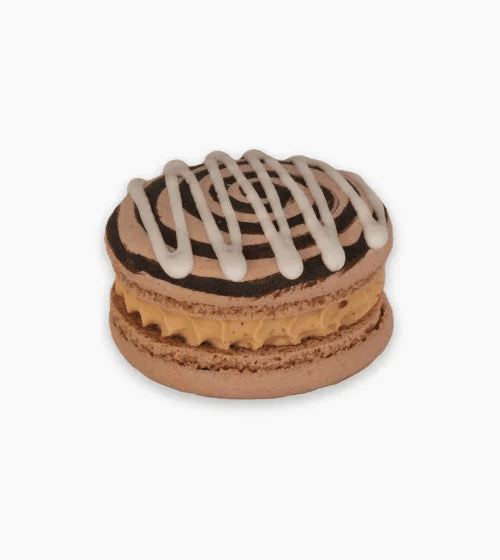 Close-up of a cinnamon shell macaron with cinnamon-vanilla ganache and chocolate drizzles