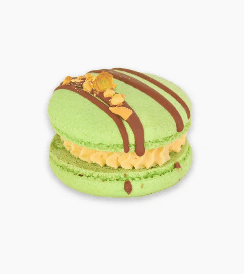 Bright green pistachio macarons with chocolate drizzle and crunchy nuts, perfect for gifting or pairing with coffee or champagne
